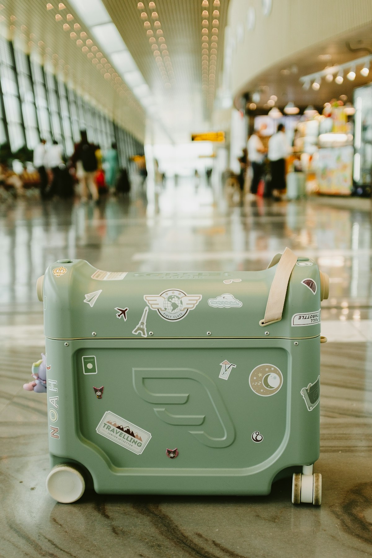 Mala verde com adesivos em um terminal de aeroporto.