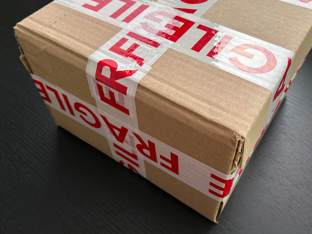 Caixa de papelão fechada com fita de aviso de material frágil.
