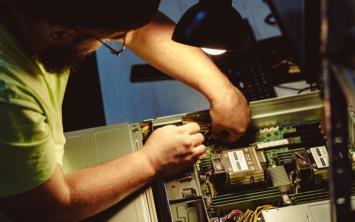Homem trabalha com componentes no interior de um computador.