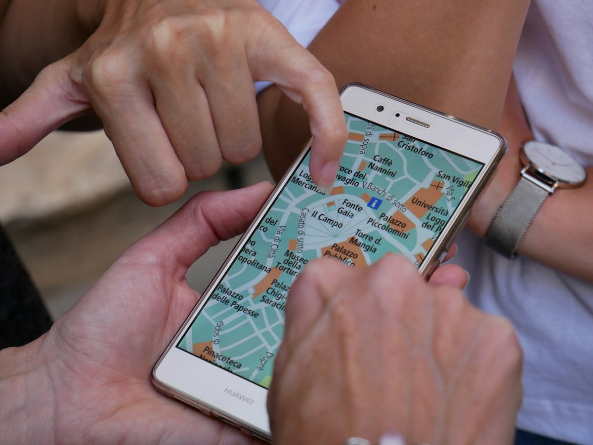 Mãos apontam para um mapa exibido no smartphone.
