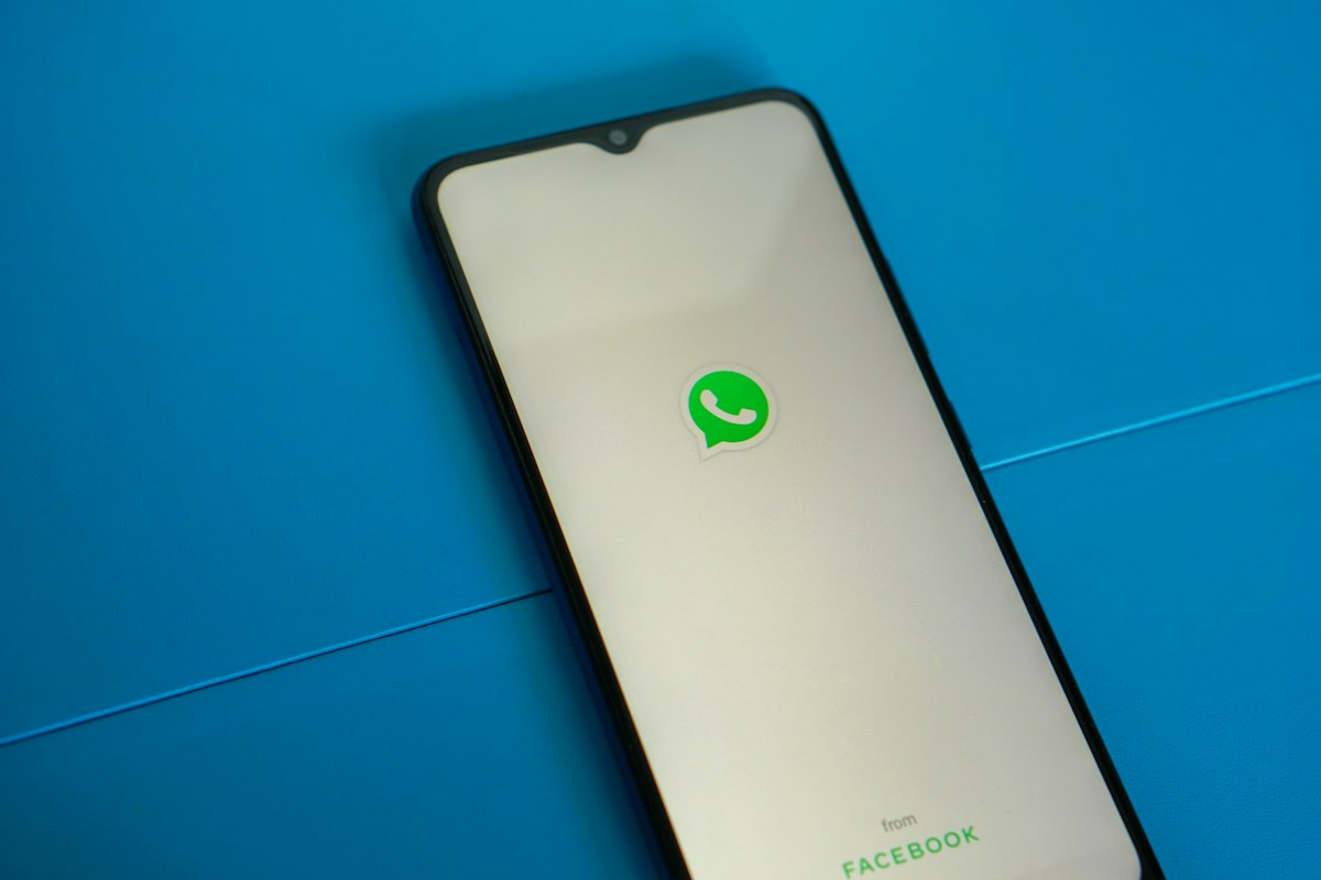 Smartphone sobre fundo azul com a marca do WhatsApp na tela.