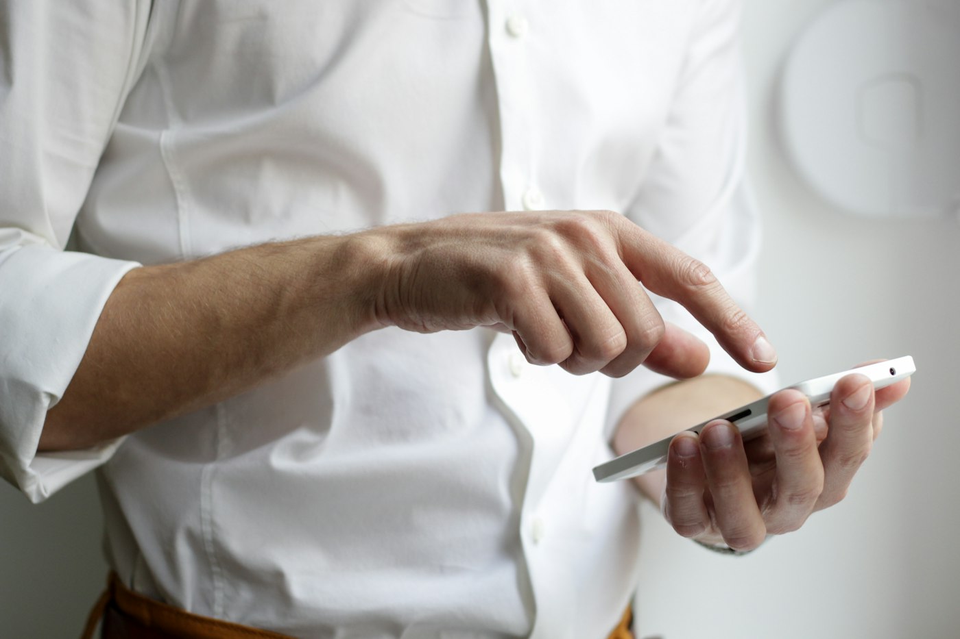 Mãos de uma pessoa usando um smartphone branco.